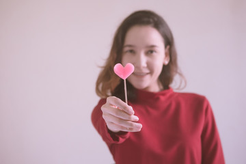 Portrait of Happy asian woman dressed in red sweater holding pink heart candy.