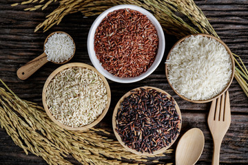 Closeup Brown rice, Black Jasmine rice, Red jasmine rice and Riceberry in bowl on wooden desk.