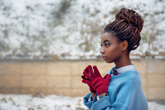 African women in vintage style and bright makeup is in profile warming hands in the winter on snow background close up outdoor