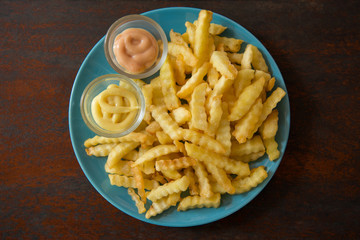 Top view of fried potatoes and salad sauce in a dish placed on a wooden table.
