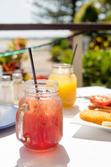 Fresh juice in mason jars with straws and also a cooked breakfast.