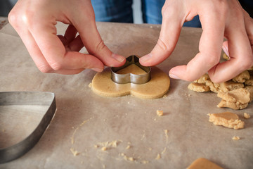 woman making homemade ginger cookies in the form of hearts on a wooden table.