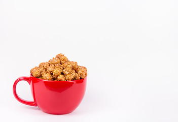 Golden caramelized popcorn in red bowl on white background. Harmful delicious sweets. Sweets for the cinema