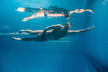 underwater picture of young swimmer in goggles exercising in swimming pool