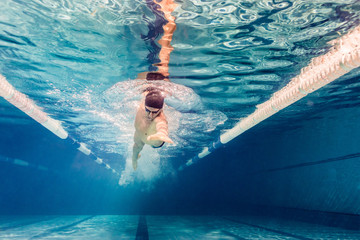 underwater picture of young swimmer in goggles exercising in swimming pool - obrazy, fototapety, plakaty