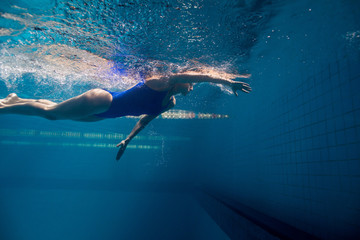 underwater picture of young female swimmer exercising in swimming pool