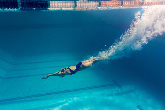 underwater picture of young female swimmer exercising in swimming pool
