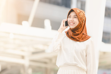 Portrait happy muslim young woman using mobile phone in city