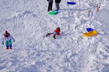 スキー場でそり遊びをする子供たち