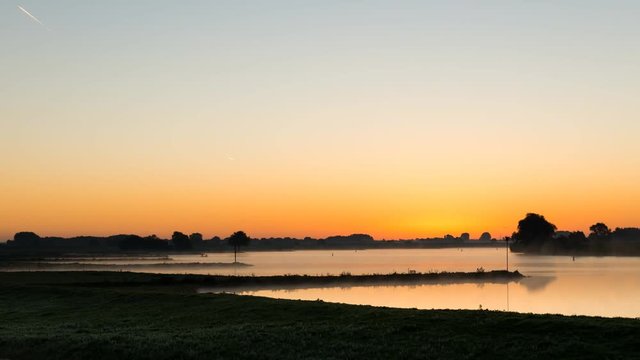 Time lapse of the sunrise at the river Lek with boats near Culemborg, The Netherlands.