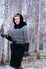 Happy and smiling woman on weekend. Lady in a striped coat walks on the street enjoying fresh air...