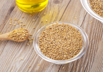 Bottle of flax seed oil ans seeds on wooden table.