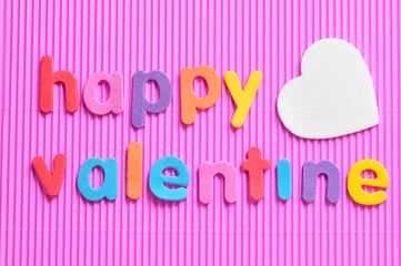 Happy valentine in colorful letters on a pink background with a white heart