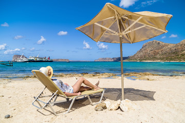 Woman on the beach lying under umbrella