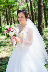 Adorable young beautiful bride with bouquet in hands.