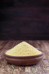 Millet in a wooden bowl standing on the kitchen table made of oak. 