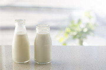 Two bottles of milk on table.