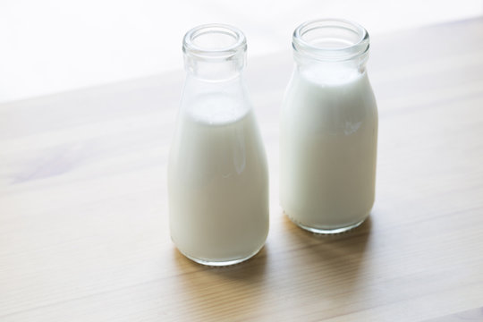 Two bottles of milk on table.