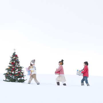 クリスマスツリーとプレゼントを運ぶ子供たち