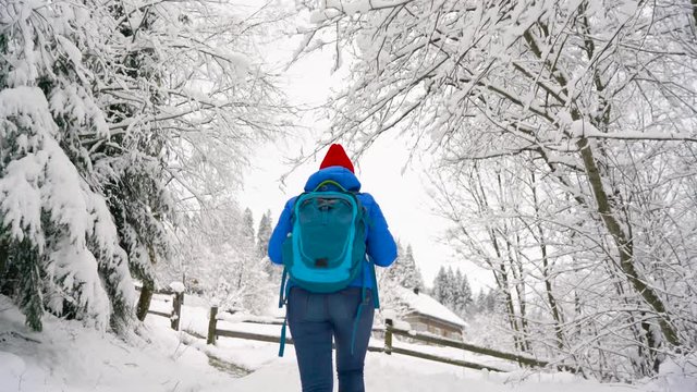 Woman climbs on a snow-covered mountain, turns around, smiling and waving to somebody hand. Clear sunny frosty weather