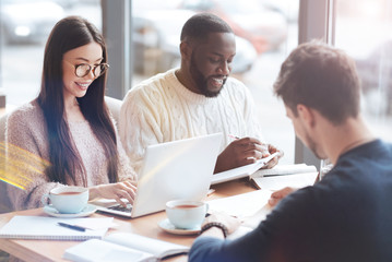 Working at project. Attractive bearded man bowing his head while making notes and expressing positivity
