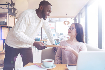 Obraz premium Consult me please. Confident international male person standing in semi position and leaning on the chair while talking to his pretty colleague