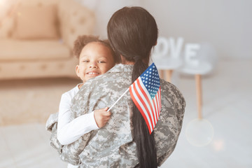 Patriot of the country. Cheerful positive cute girl hugging her mother and smiling while holding an...