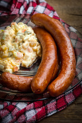 Thin sausages with vegetable salad on plate.