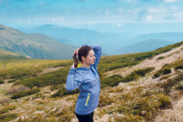 Naklejka premium Young fitness woman in sportswear poses at the beautiful mountains