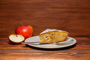 Fresh apples and a piece of apple pie sprinkled with powdered su