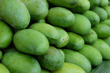 Pile of sweet and sour green raw mangoes prepared for selling in market