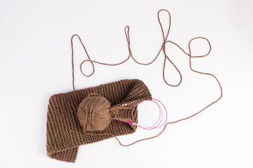 knitted scarf of brown thread and a ball on a white background