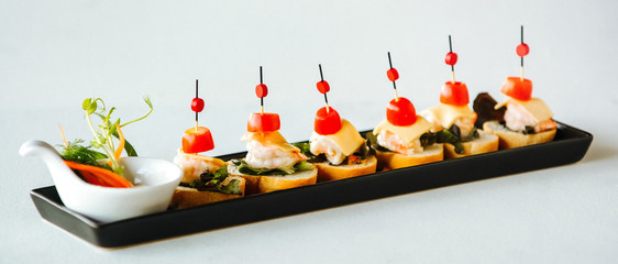 Shrimp cheese and tomatoes on a skewer with bread. Buffet, treats on the table