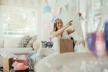 Pregnant woman opening a new gift after baby shower
