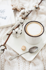 Obraz na płótnie Canvas Mug of hot drink with cotton branch on white cozy winter blanket