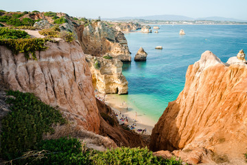 Camilo Beach in Lagos, Algarve, Portugal. A tiny secret beach between the limestone walls. 200 wooden steps down to sheltered, sandy cove divided by ochre-colored rocks with hand-dug tunnel.