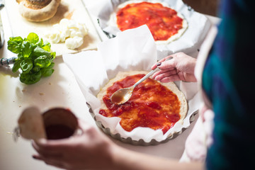 Baking pizza at home, top view of the dough, tomato and other ingredients. Concept of home made food
