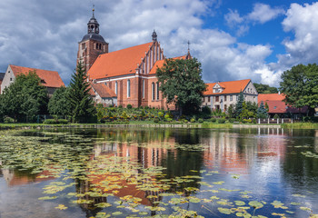 Pond on Pisa River and Saints Anne and Stephen Catholic Church in Barczewo, small city near Olsztyn, Masuria region of Poland - obrazy, fototapety, plakaty