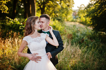 Newly married couple enjoying each other's company in the forest at sunset on their wedding day.