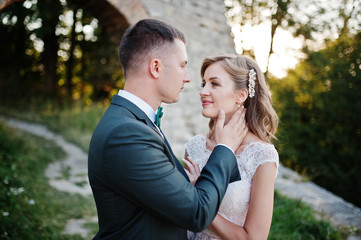 Fototapeta premium Bride and groom smiling and having great time in the forest next to the old brick bridge.