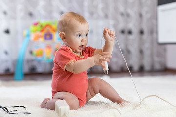 baby boy pulling cables from electrical extension