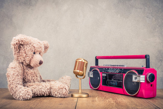 Retro Teddy Bear toy, classic golden mic and old outdated cassette radio recorder from 80s front concrete wall background. Music recording concept. Vintage style filtered photo