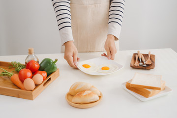 Hands of man prepare breakfast with eggs and bread.