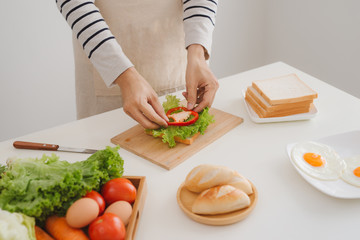 Hands of man prepare sandwich at home.