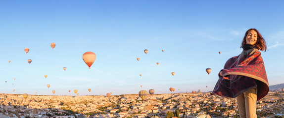 A woman travels through Cappadocia at the background of a grandiose balloon show in Turkey