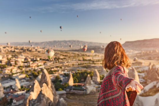 A woman travels through Cappadocia at the background of a grandiose balloon show in Turkey