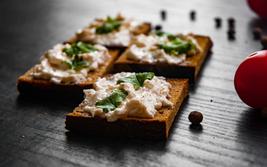 Slices of bread with cream cheese on a dark wooden background