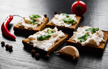 Slices of bread with cream cheese on a dark wooden background