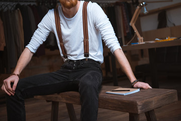 cropped shot of stylish male fashion designer sitting with notebook at workplace