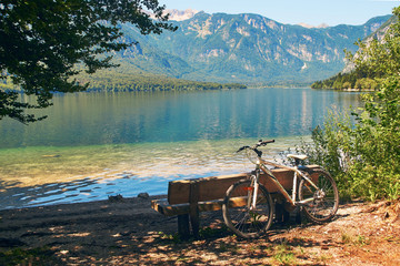 Fototapeta na wymiar Mountain bike parked near the wooden bench on the shore of lake Bohinj